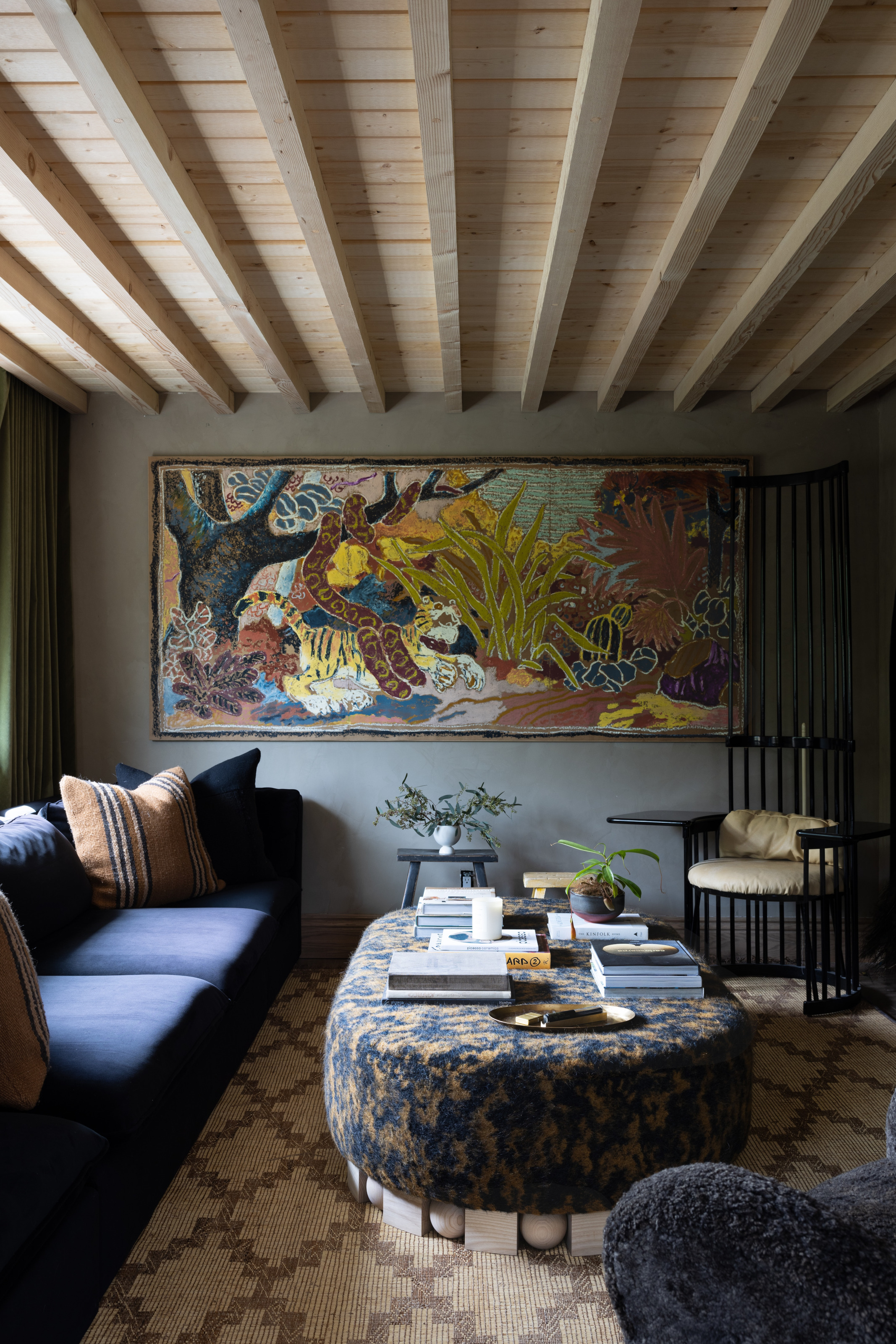 Snug with grey blue walls, jungle artwork, patterned upholstered ottoman and blue sofa