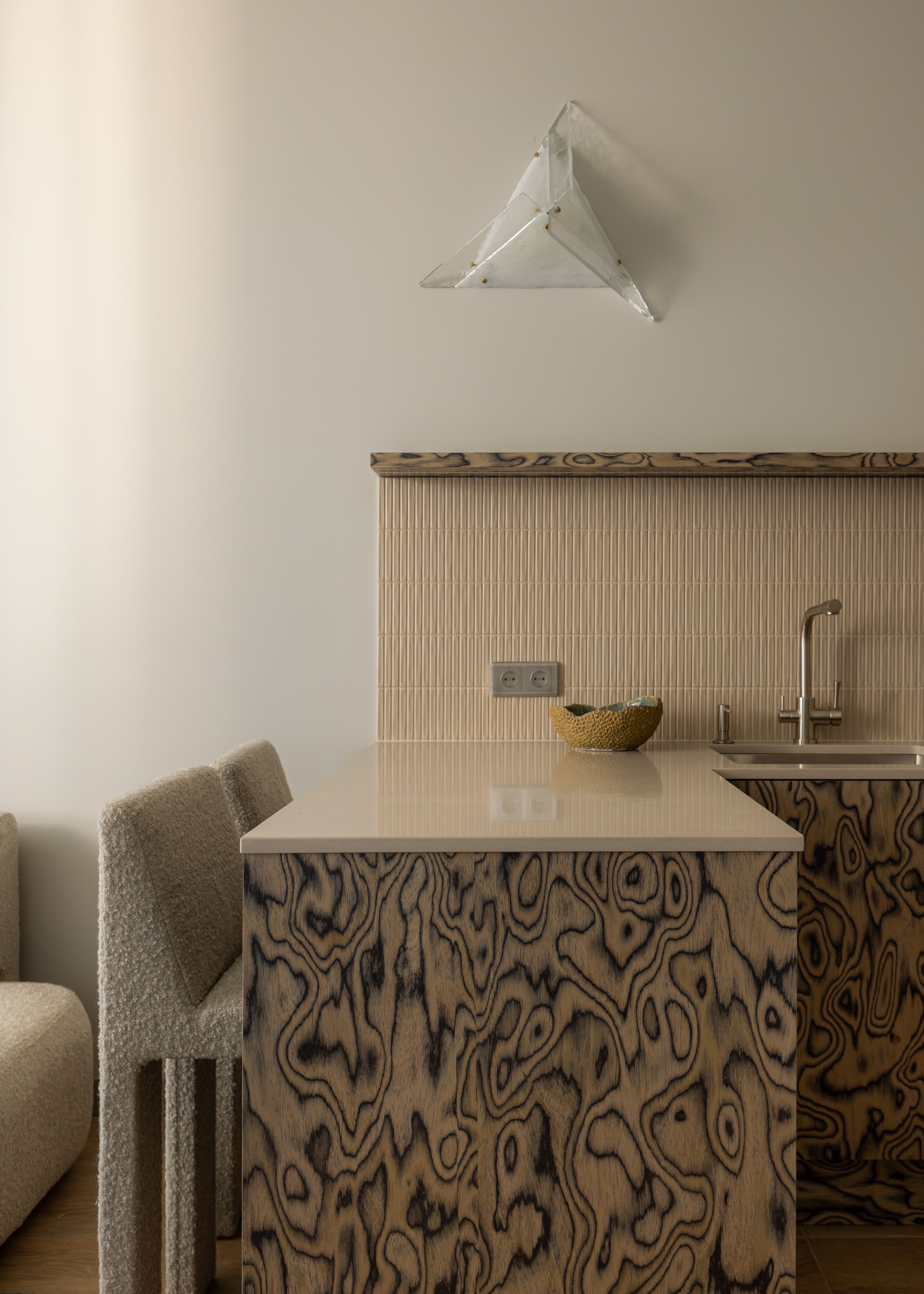 A small, compact kitchen wuth woode veneer on the island and zellige tiles on the backsplash