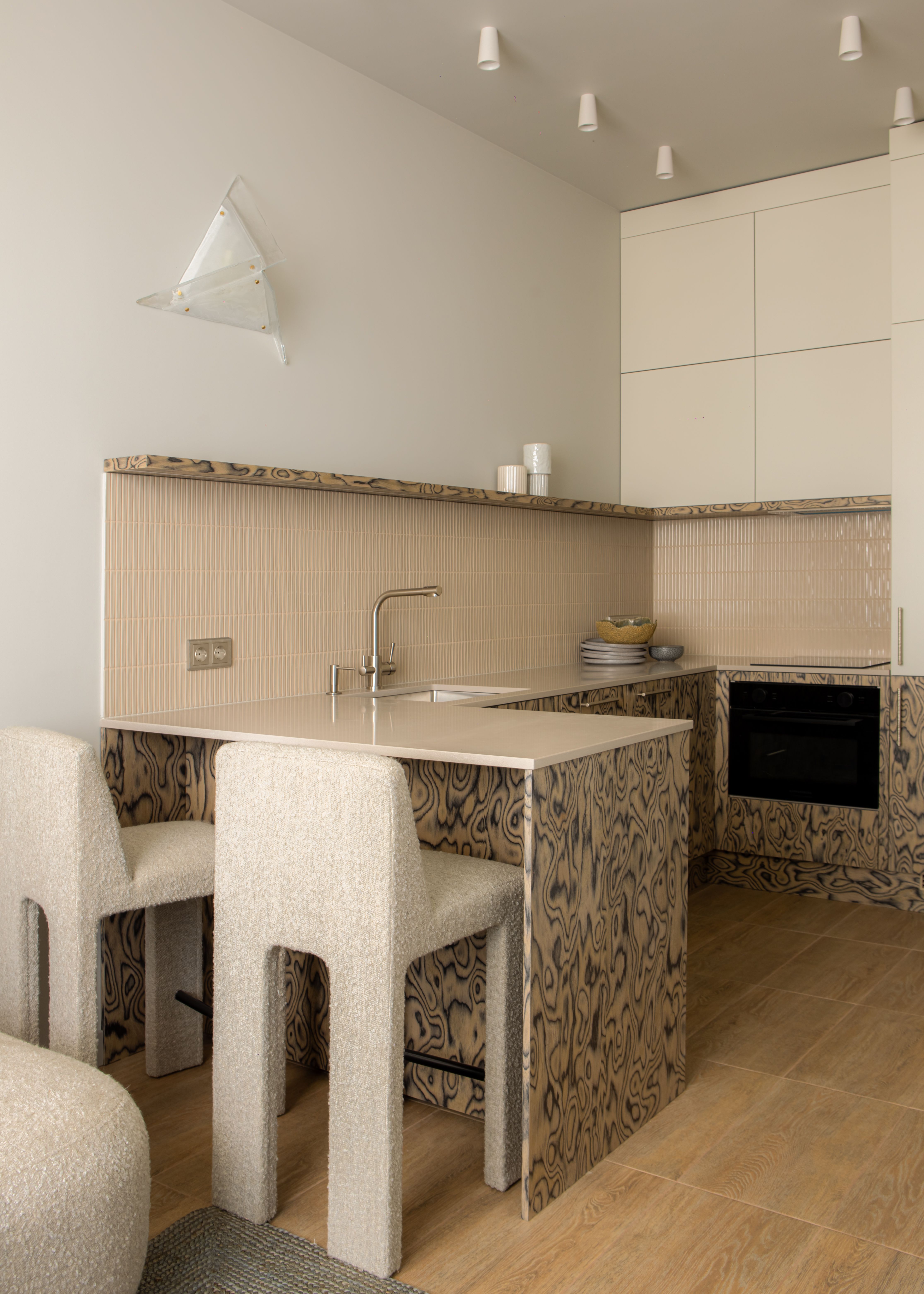 A small, compact kitchen wuth woode veneer on the island and zellige tiles on the backsplash