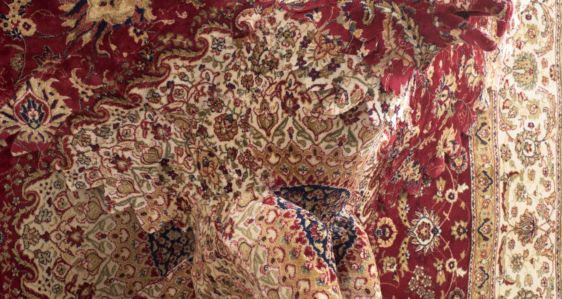 a detail of a large wall sculpture by Debbie Lawson made from ornamental woven carpet, with the silhouette of an eagle flying out of the center