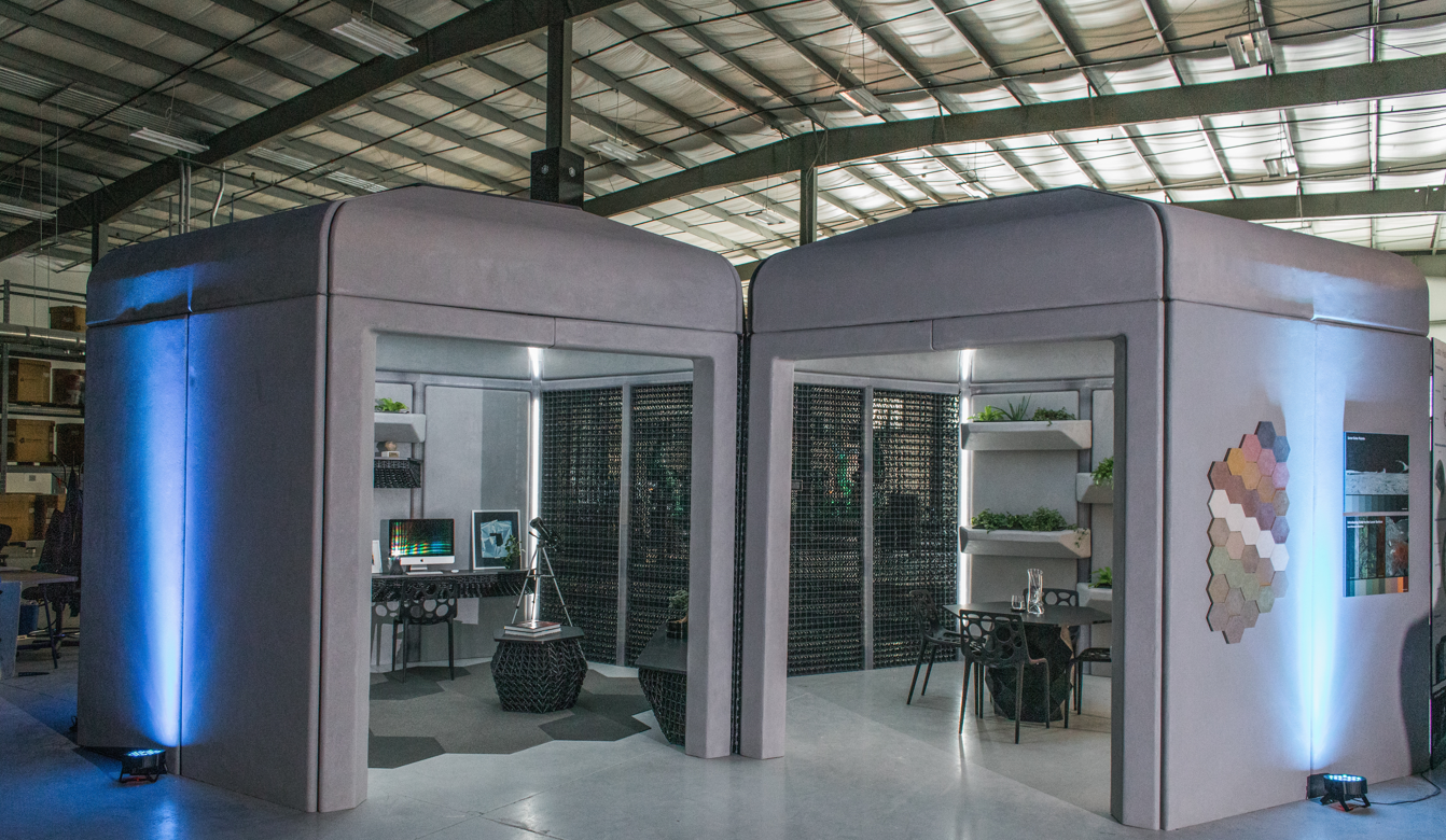Two boxy structures, one with an office-like interior and the other with an eating area, side-by-side in a hangar-like location