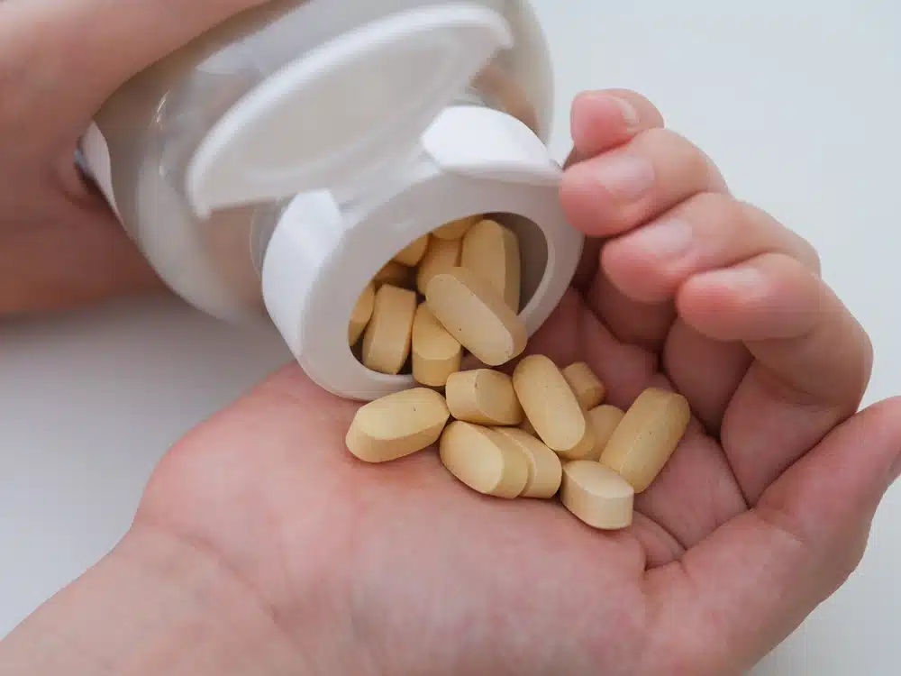 A,young,man,pouring,magnesium,taurate,tablets,out,of,a