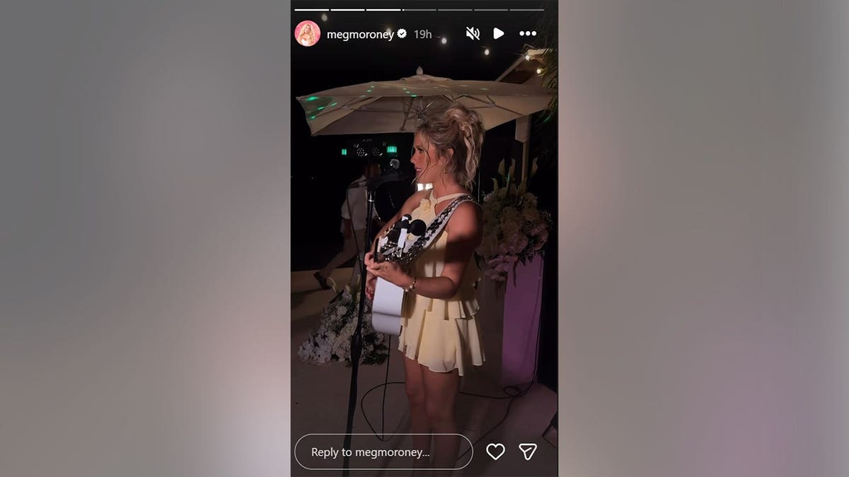 Megan Moroney playing the guitar in a yellow dress in May 2026.