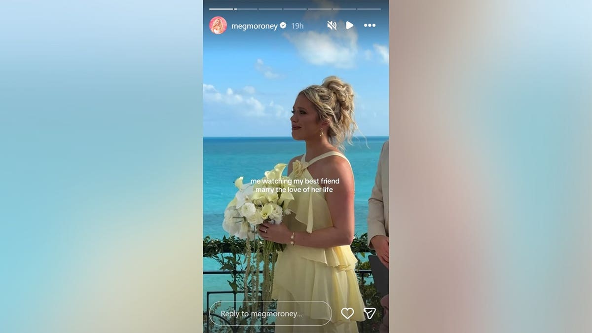 Megan Moroney in a yellow dress and holding a bouquet with the ocean behind her in May 2026.