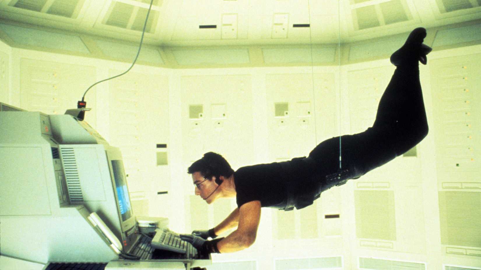 Tom Cruise hangs suspended by wires at a computer terminal