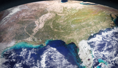 Satellite view of the eastern United States from space during autumn, showing the curve of the Earth, changing leaf colors across the Appalachian Mountains, and vibrant turquoise sediment plumes swirling in the Gulf of Mexico.
