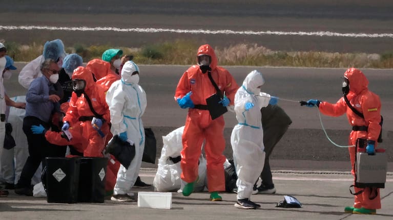 Passengers are sprayed with disinfectant by Spanish government officials before boarding a plane after disembarking from the hantavirus-stricken cruise ship MV Hondius at Tenerife airport in the Canary Islands, Spain, Sunday, May 10, 2026.