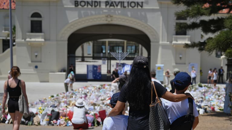 People visit a floral tribute outside the Bondi Pavilion following Sunday's shooting at Bondi Beach.