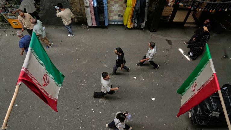 People walk as Iranian flags hang in the Grand Bazaar in Tehran, Sunday, May 3, 2026.