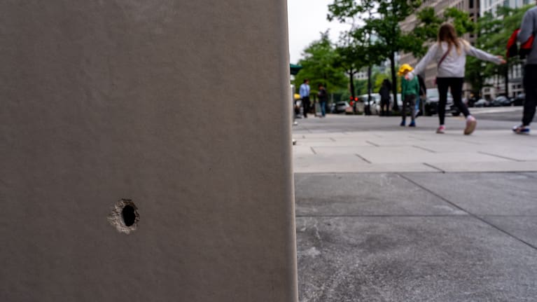 People walk past a hole in the wall of a building near the scene of a shooting close to the White House, Sunday, May 24, 2026, in Washington.