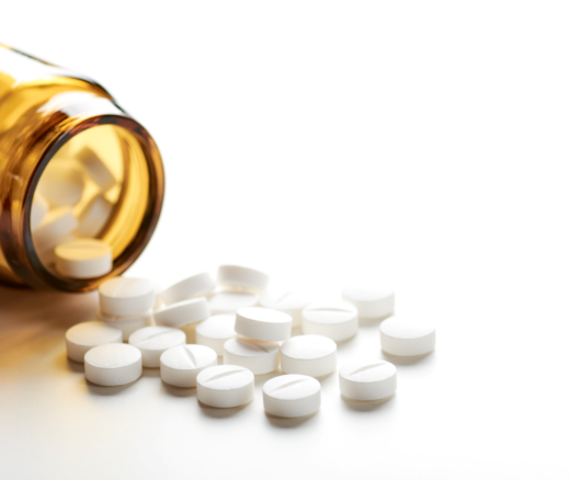 An image of white pills spilling out of a bottle onto a white surface