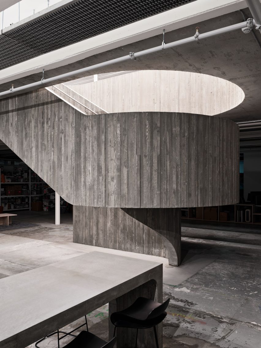 A concrete staircase with a curved landing connecting its two parallel flights