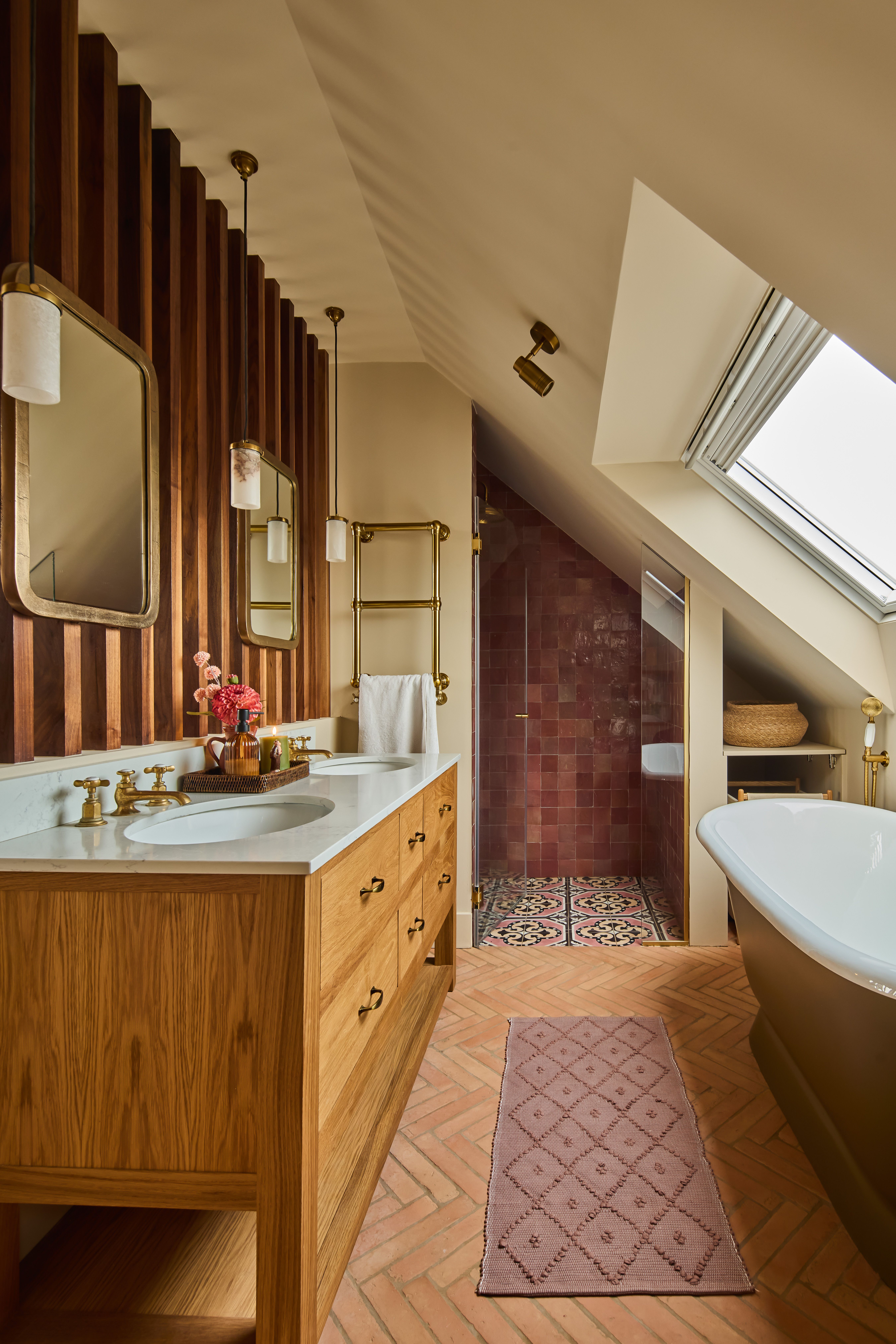 a loft ensuite bathroom with a vanity, bath, shower with red tiles, and slanted roof with a roof light