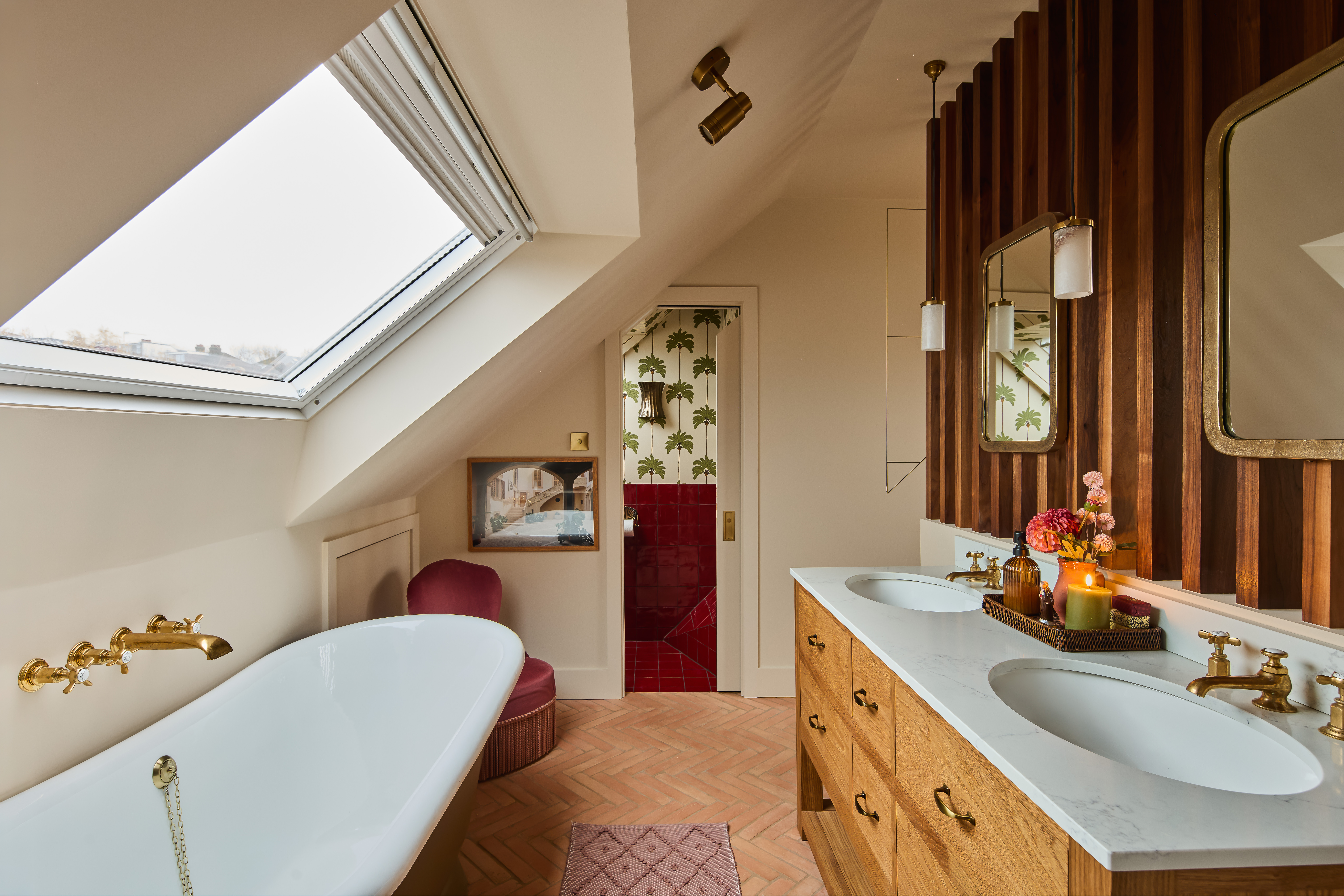 a loft bathroom with a large roof light, a bath, vanity and enclosed WC in red tile