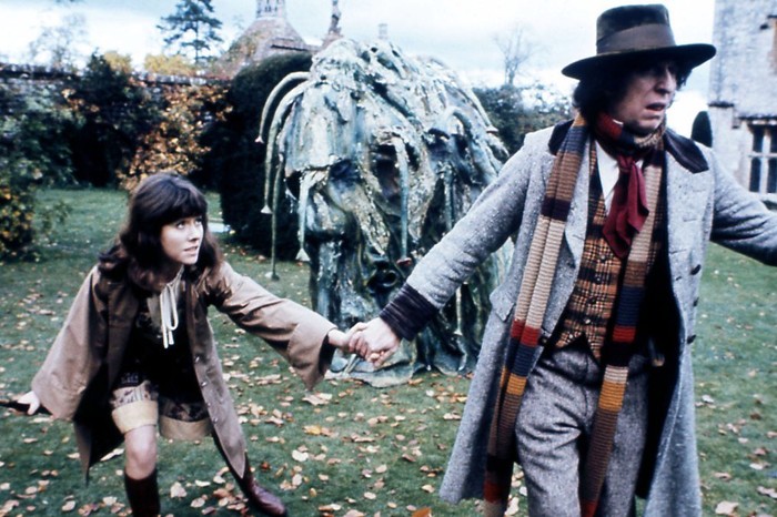 seeds-of-doom Tom Baker as the Fourth Doctor and Elisabeth Sladen as Sarah Jane Smith in 'Doctor Who: The Seeds of Doom', running hand-in-hand through a garden while being pursued by a menacing Krynoid creature, set against the backdrop of a grand estate.