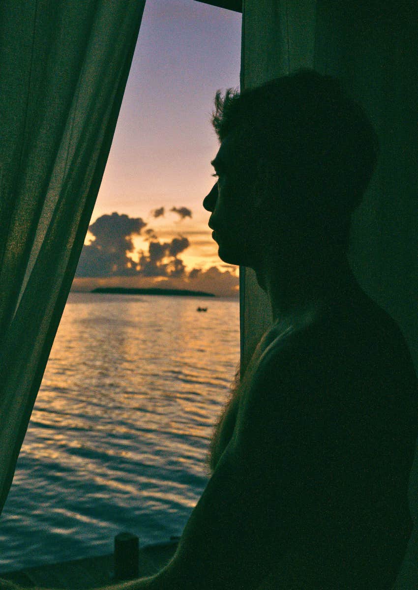 silhouette of thoughtful man looking out of window