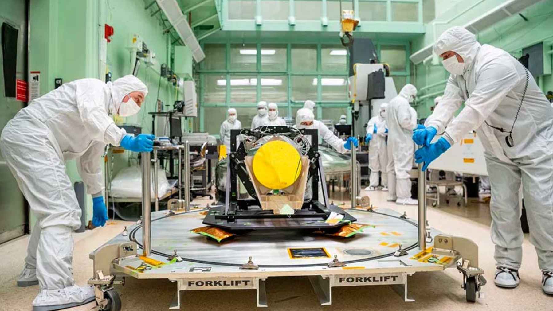 Scientists in a cleanroom handling precision scientific equipment for space or quantum experiments. 