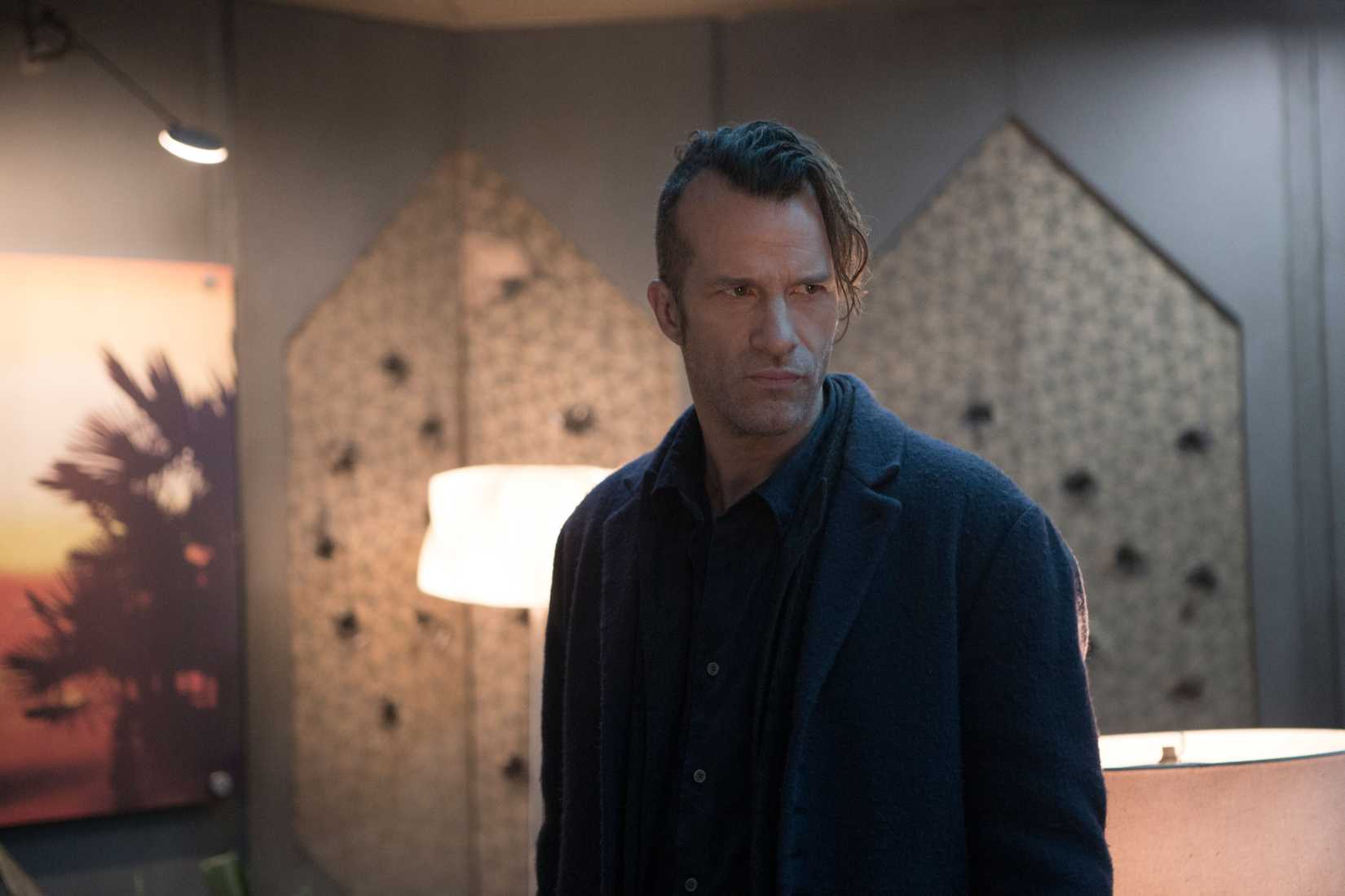Joe Miller (Thomas Jane), a narrow, glowering man in all black with one side of his head shaved, in The Expanse