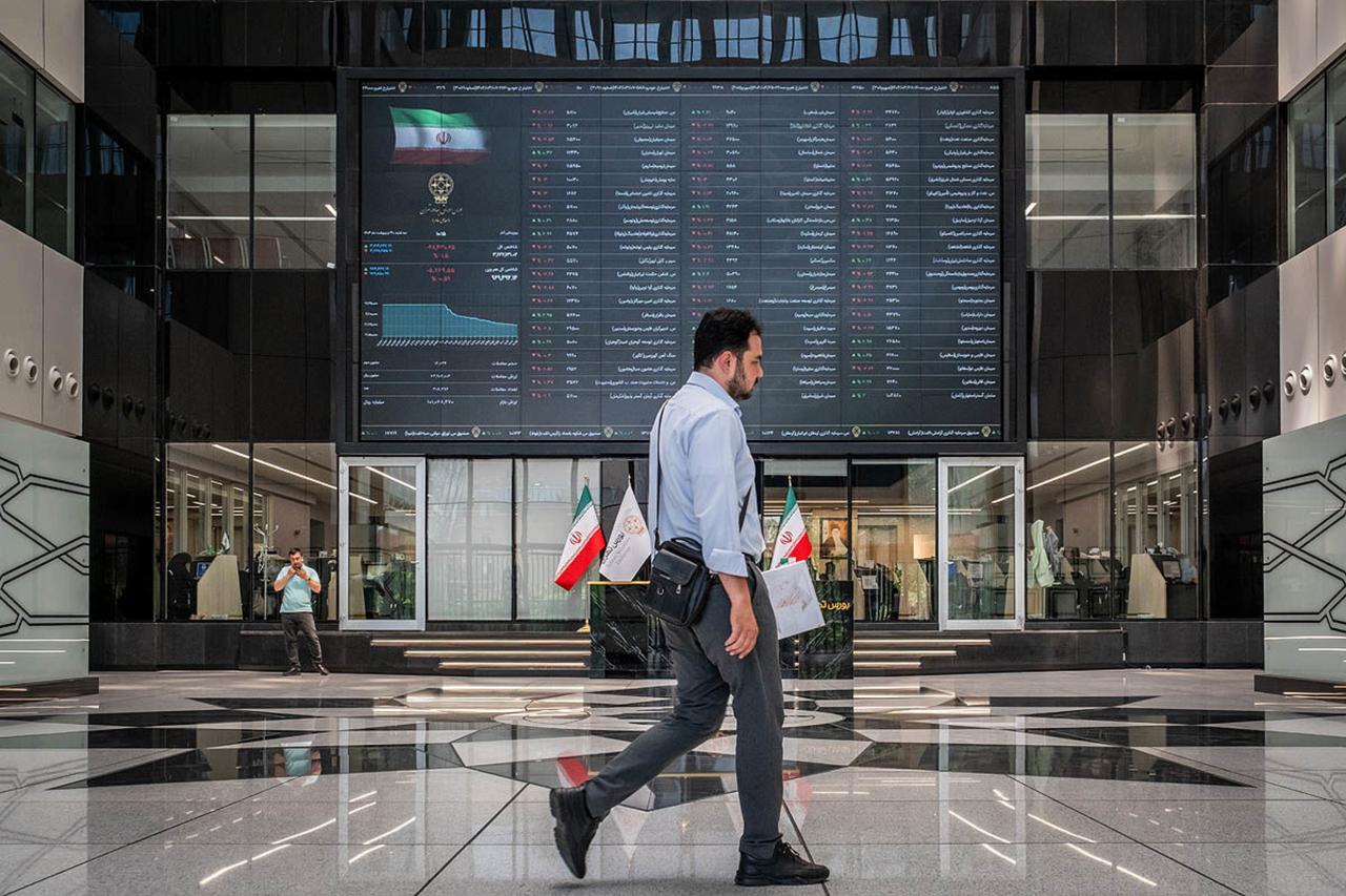 A man walks past an electronic trading board inside the Tehran Stock Exchange in Tehran, Iran. (Photo via donya-e-eqtesad.com)