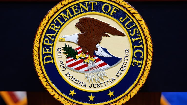 The US Department of Justice logo is seen on a podium before a news conference at the Justice Department in Washington, on May 6, 2025.