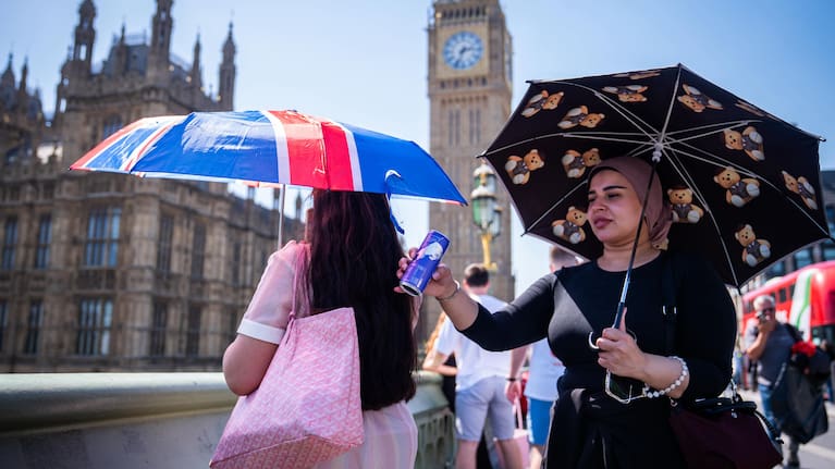 Tourists shelter from the sun beneath umbrellas during the hot weather on Westminster Bridge, central London, England, Monday, May 25, 2026.