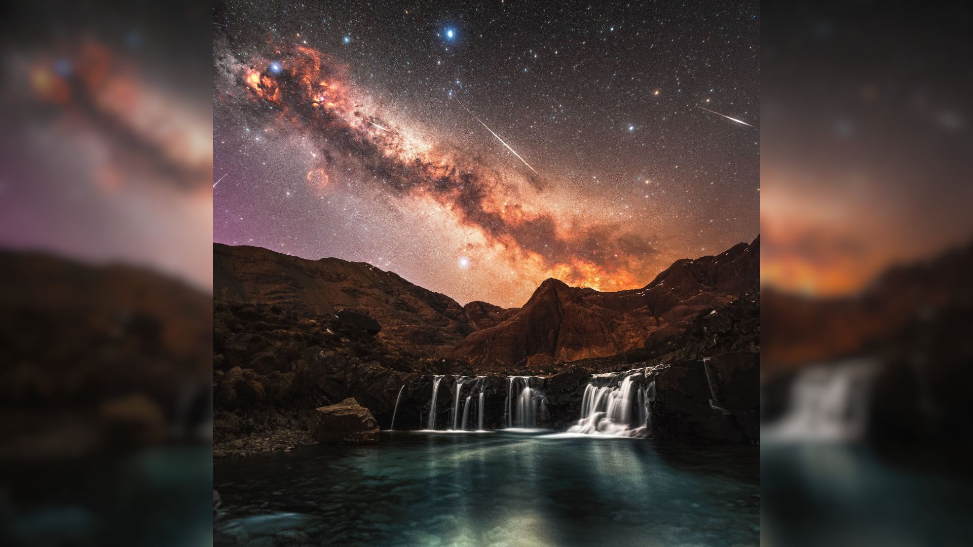 The Milky Way is pictured glowing above a series of waterfalls framed by rocky hills