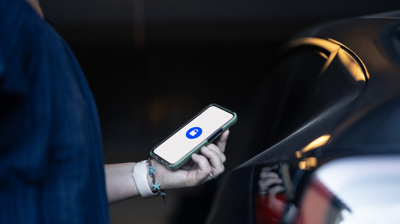 A person using a smartphone to unlock a car