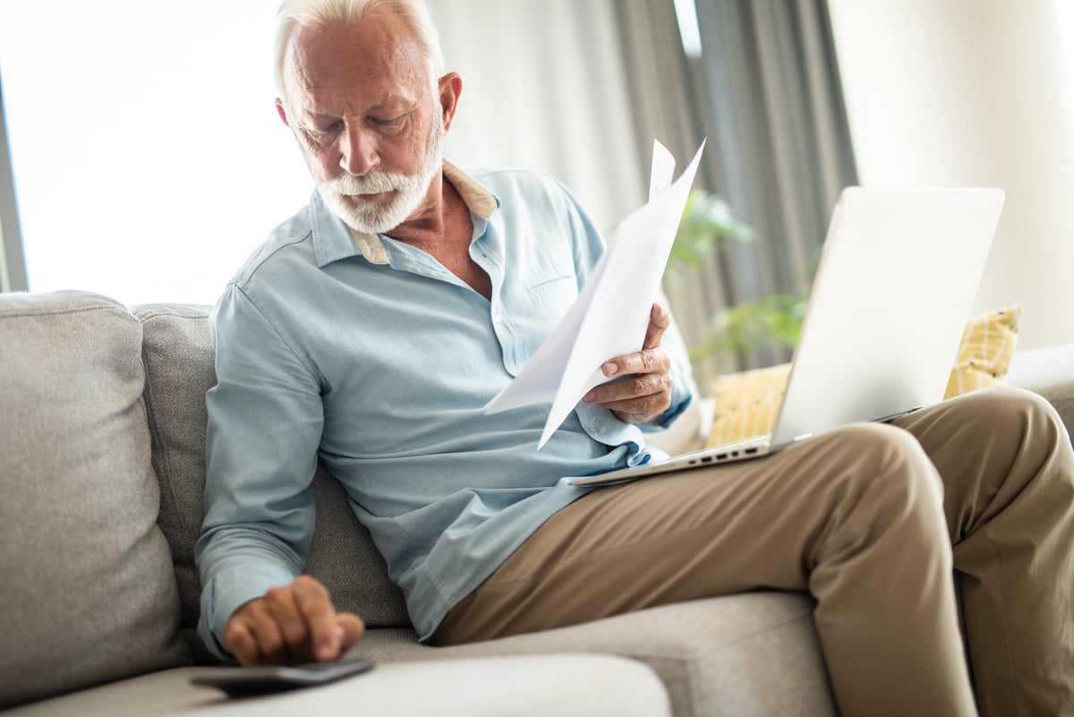 Serious person holding documents and using calculator.