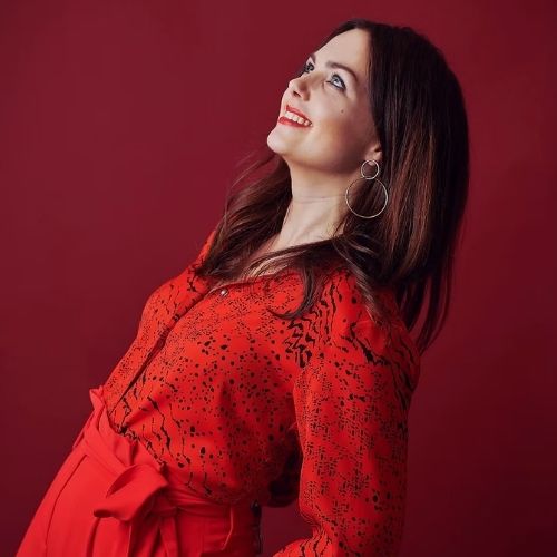 Image of a woman dressed in all red standing in front of a red background.