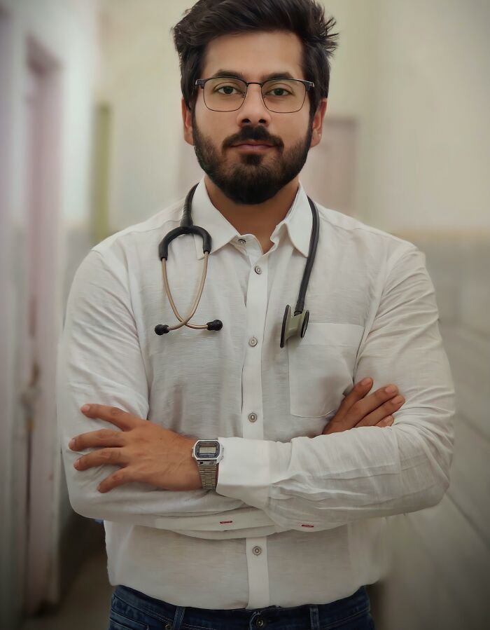 Male doctor with stethoscope and glasses standing confidently with arms crossed