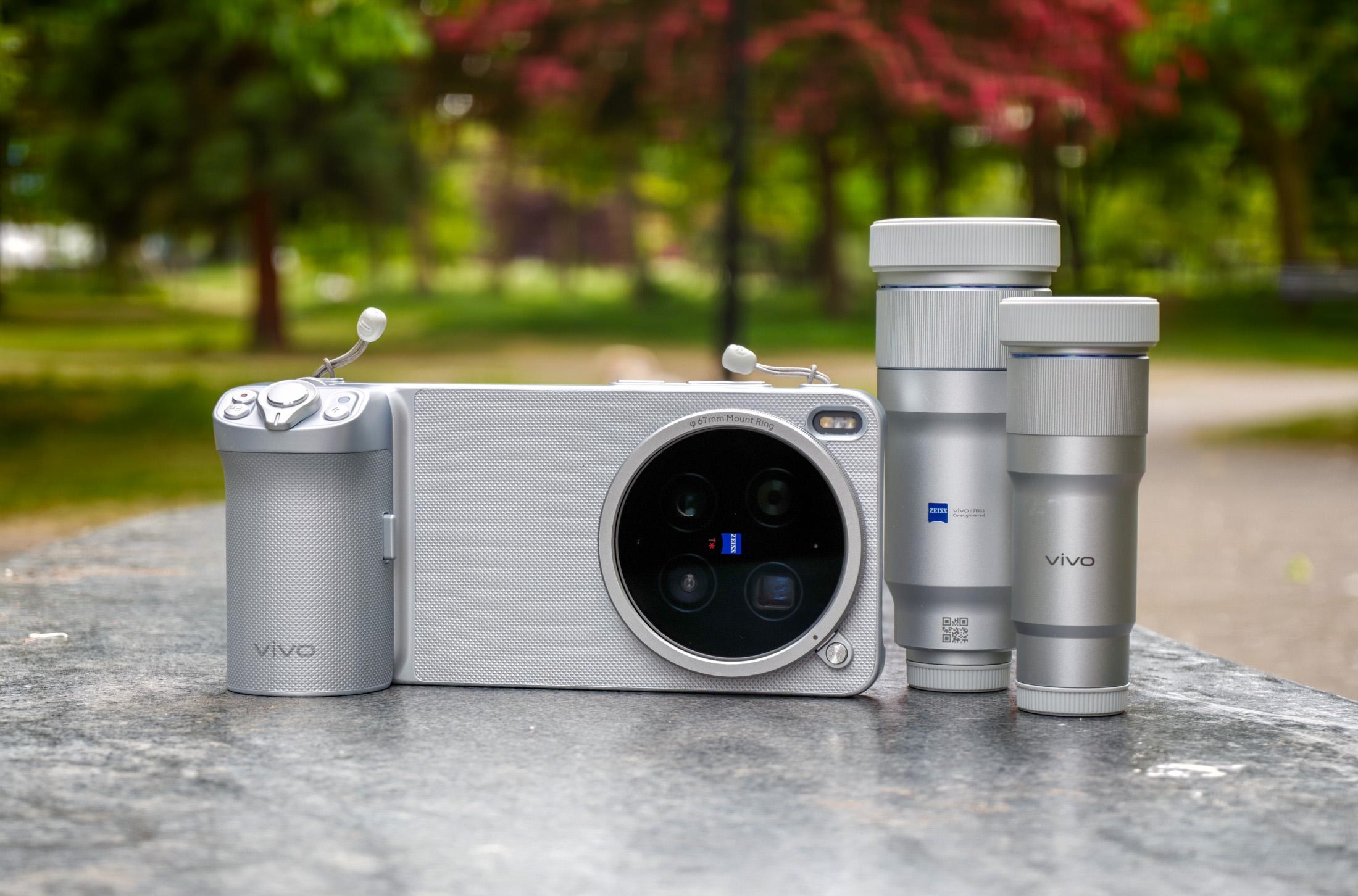 Photo of the Vivo X300 Ultra lying on a gray stone bench in the photography kit case and camera grip, with the two telephoto extender lenses next to it.