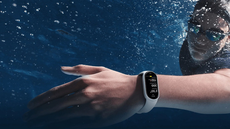 The Xiaomi Smart Band 10 on a person's right while diving underwater