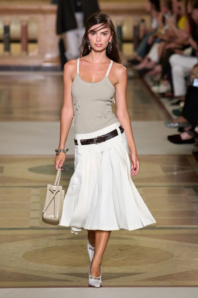 Tory Burch Spring 2026 white shirt and pleated skirt runway reference worn by Marisa Abela in London.