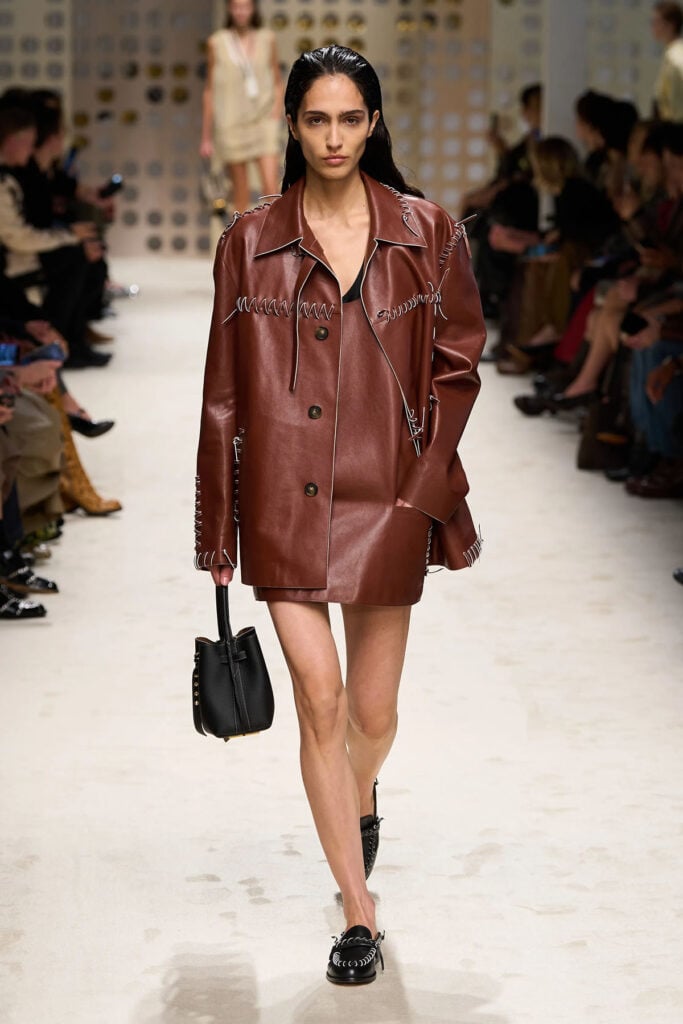 Tod's Spring 2026 brown leather dress and coat runway reference worn by Poppy Delevingne in London.