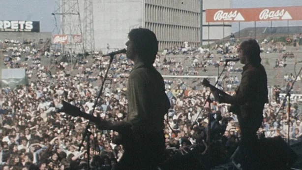 A band on stage in front of a packed stadium
