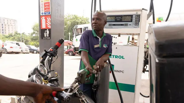 Foto of fuel attendant as e dey pump petrol into one motorcycle for fuel station for Abuja