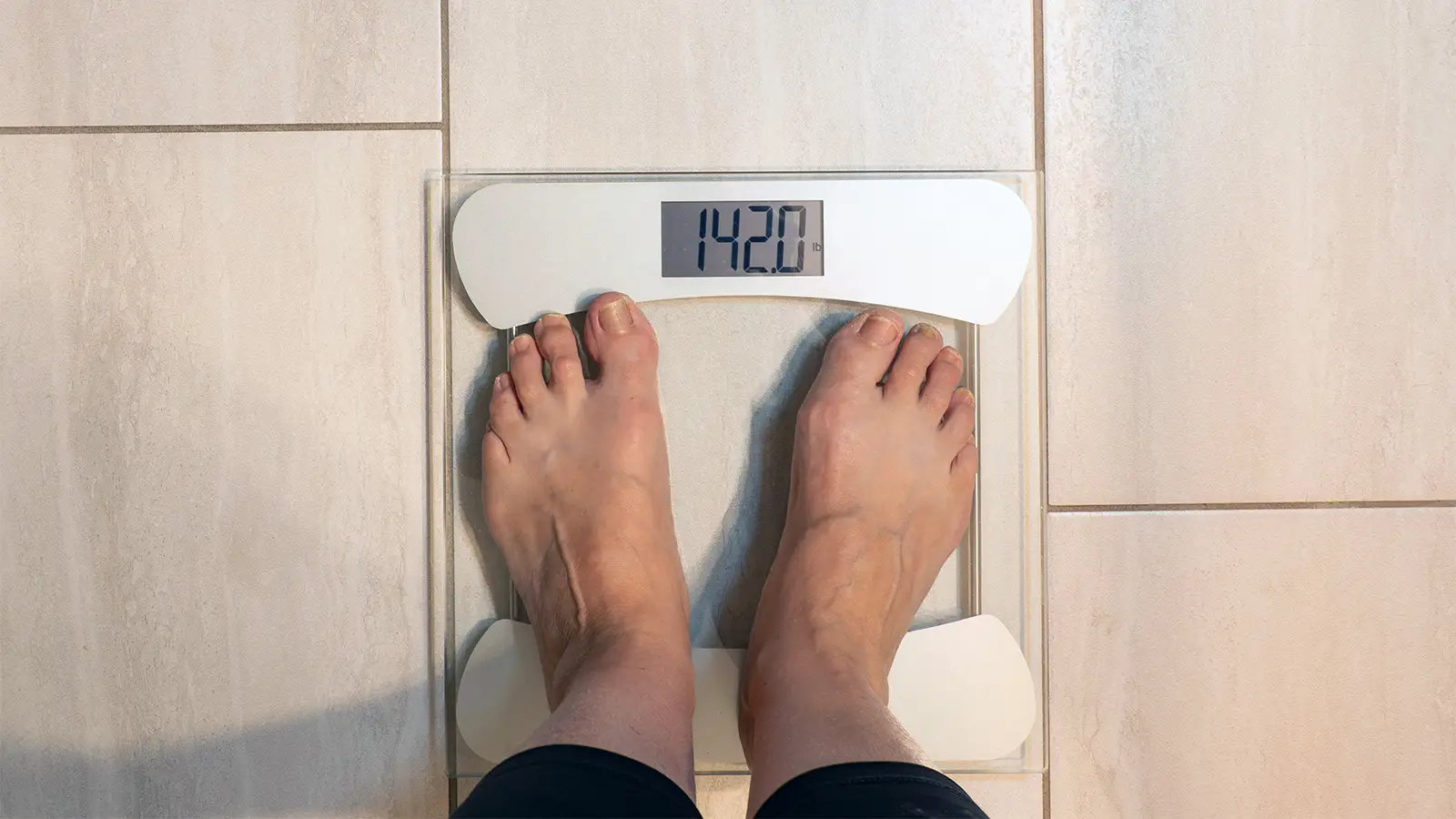A photo of a woman standing on a bathroom scale.