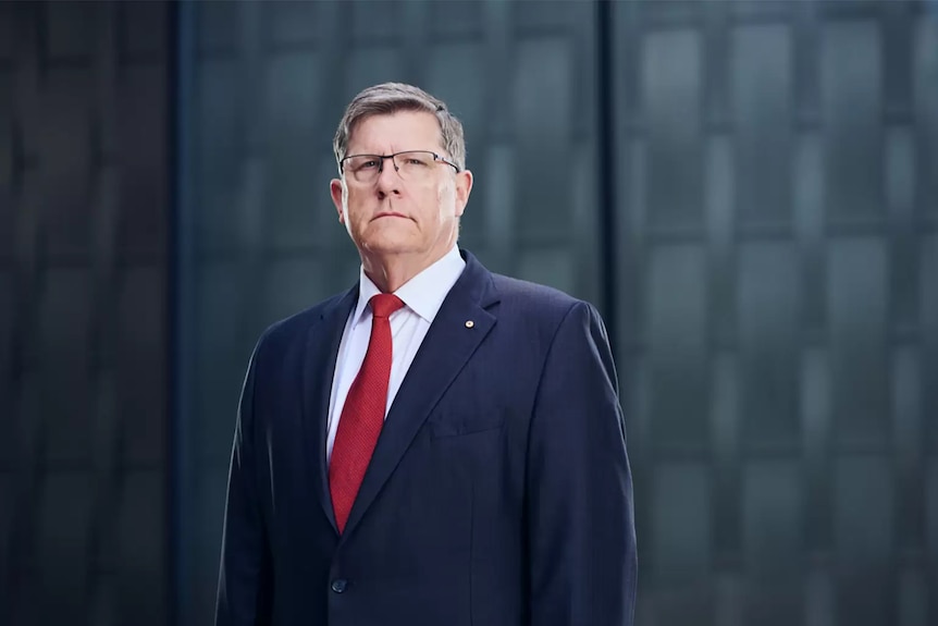 A man in a suit looks at the camera