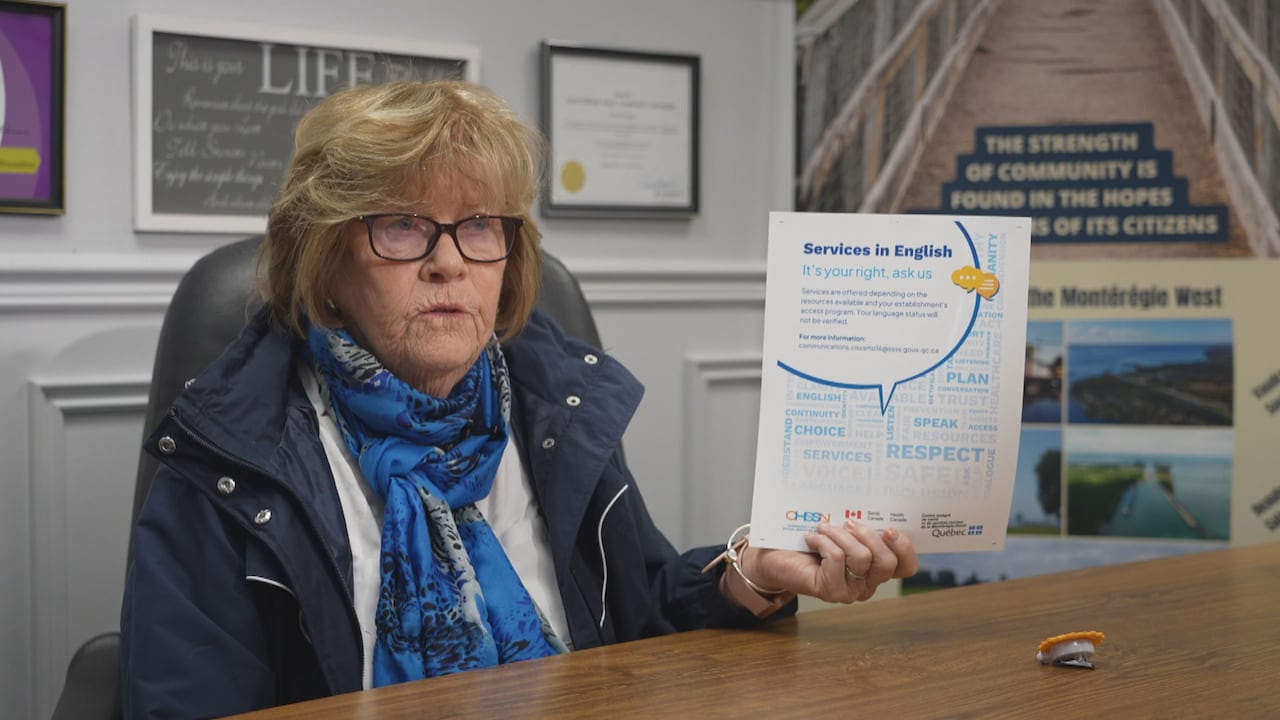 Pauline Wiedow sits at a desk, and holds up a piece of paper that says 'Services in English, it's your right, ask us"