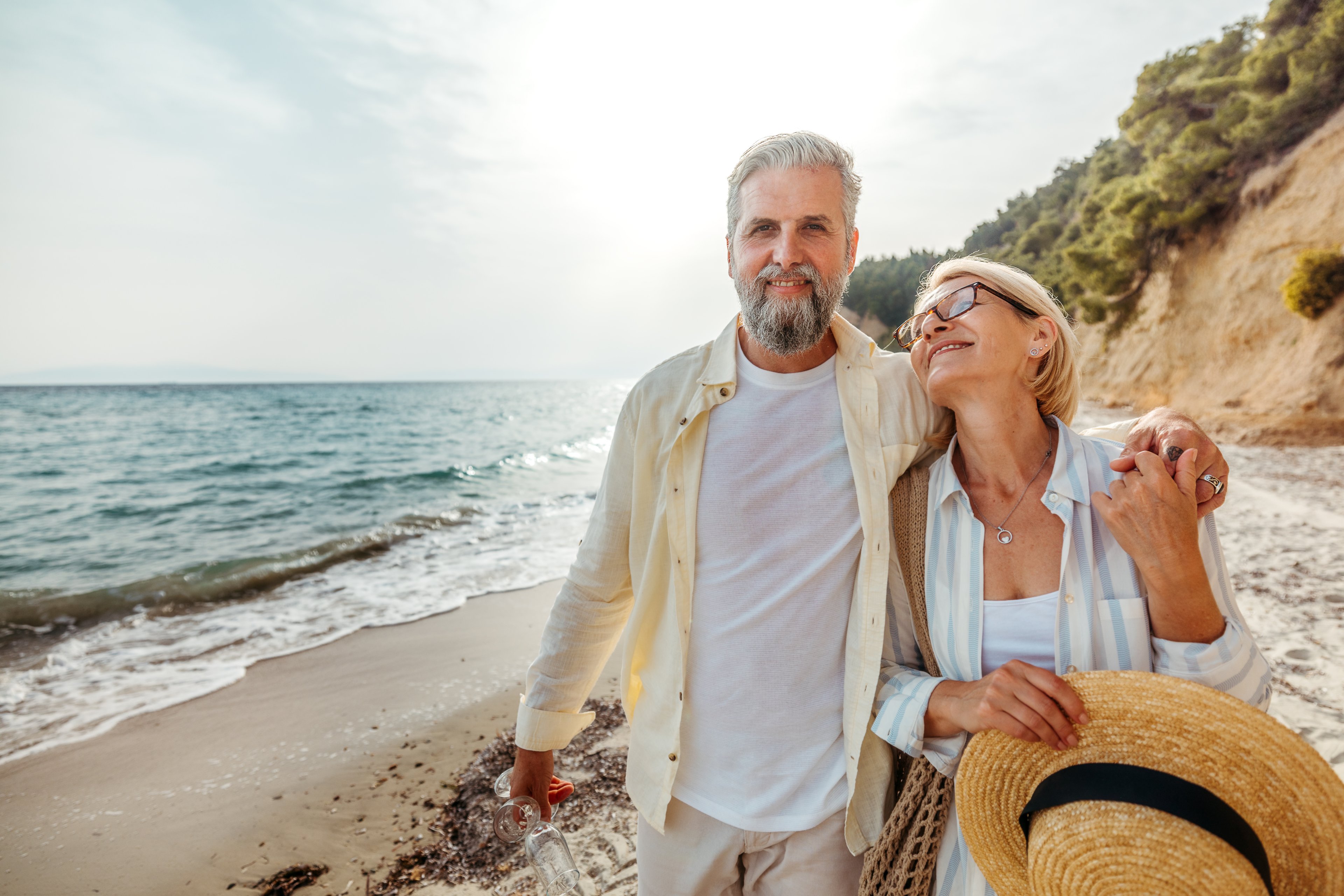 A retired couple walks along the beach.