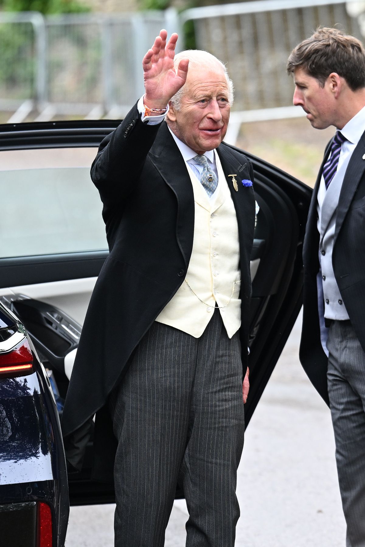 King Charles III arriving at the wedding and waving after stepping out of a car