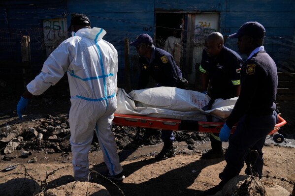 Police officers carry the body of a person on a stretcher after a mass shooting at an informal settlement in the Cleveland suburb of Johannesburg, South Africa, Wednesday, June 10, 2026. (AP Photo/Themba Hadebe)