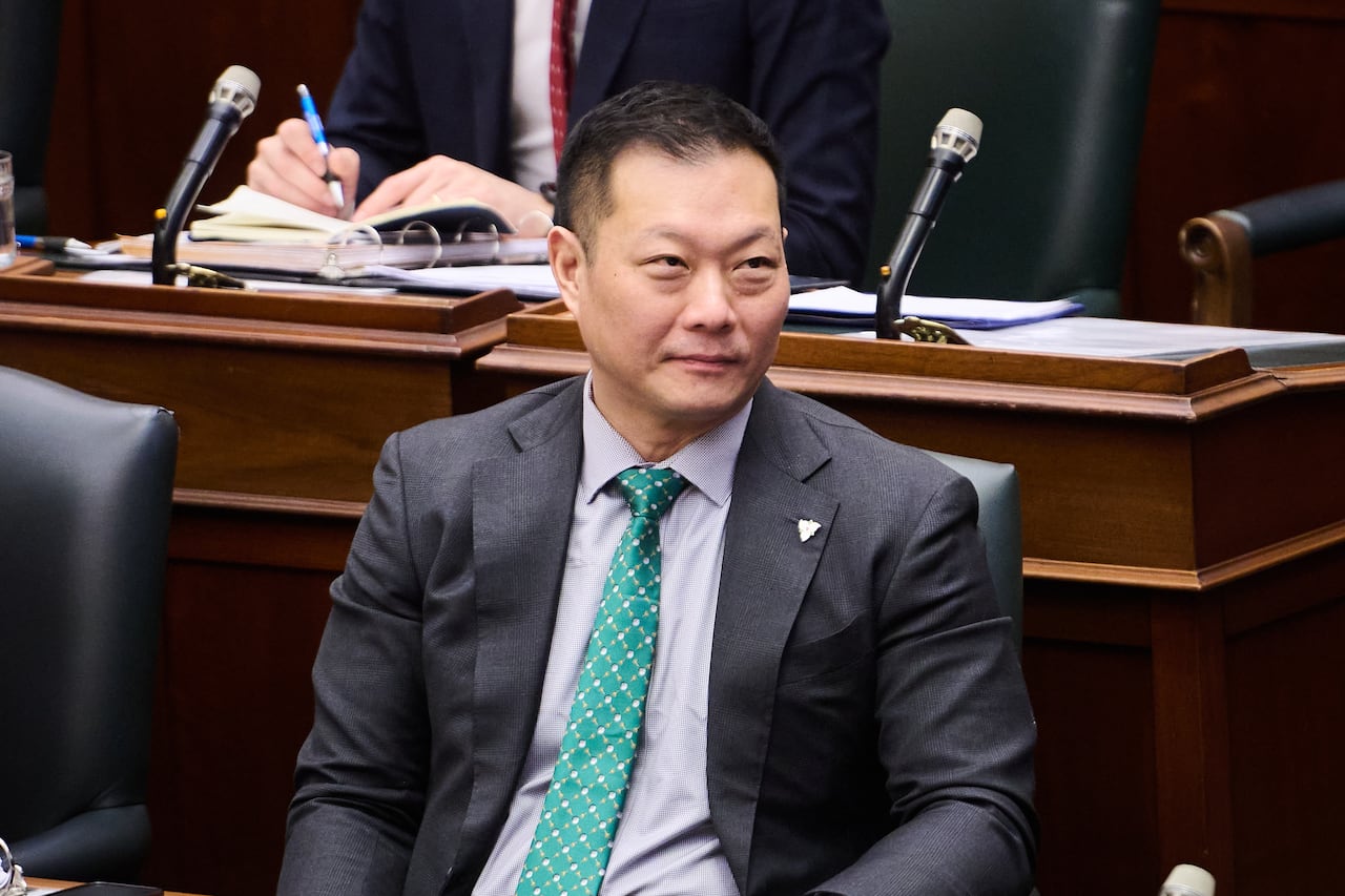 Ontario's tourism minister Stan Cho sits at Queen's Park, wearing a grey suit with a green tie.