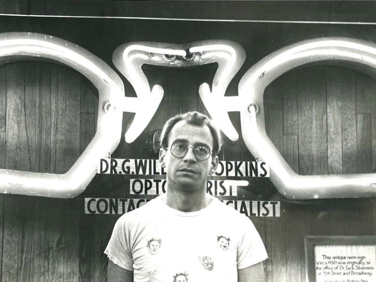 A man stands in front of an eyewear store.