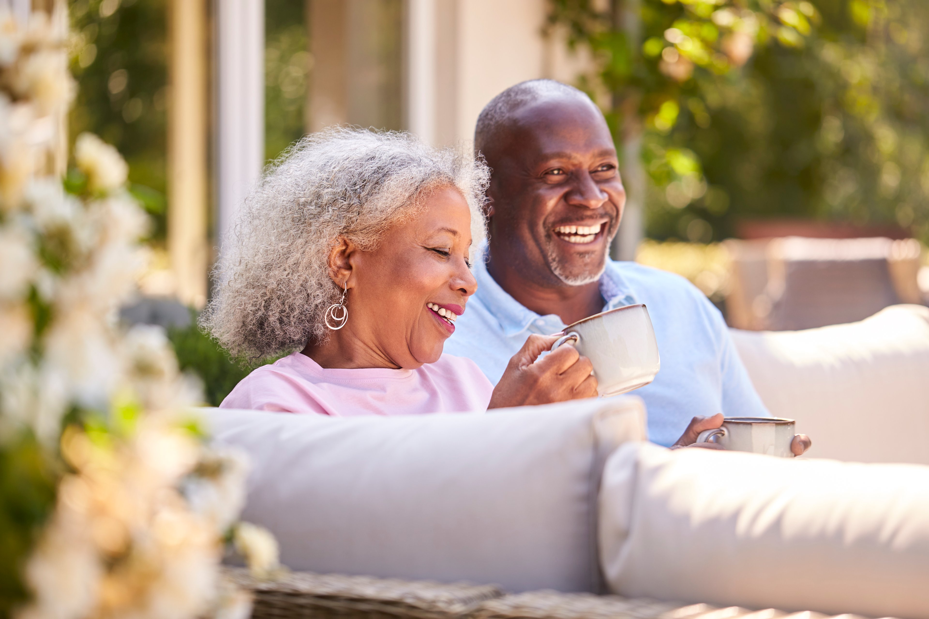 Smiling couple sipping coffee on patio.