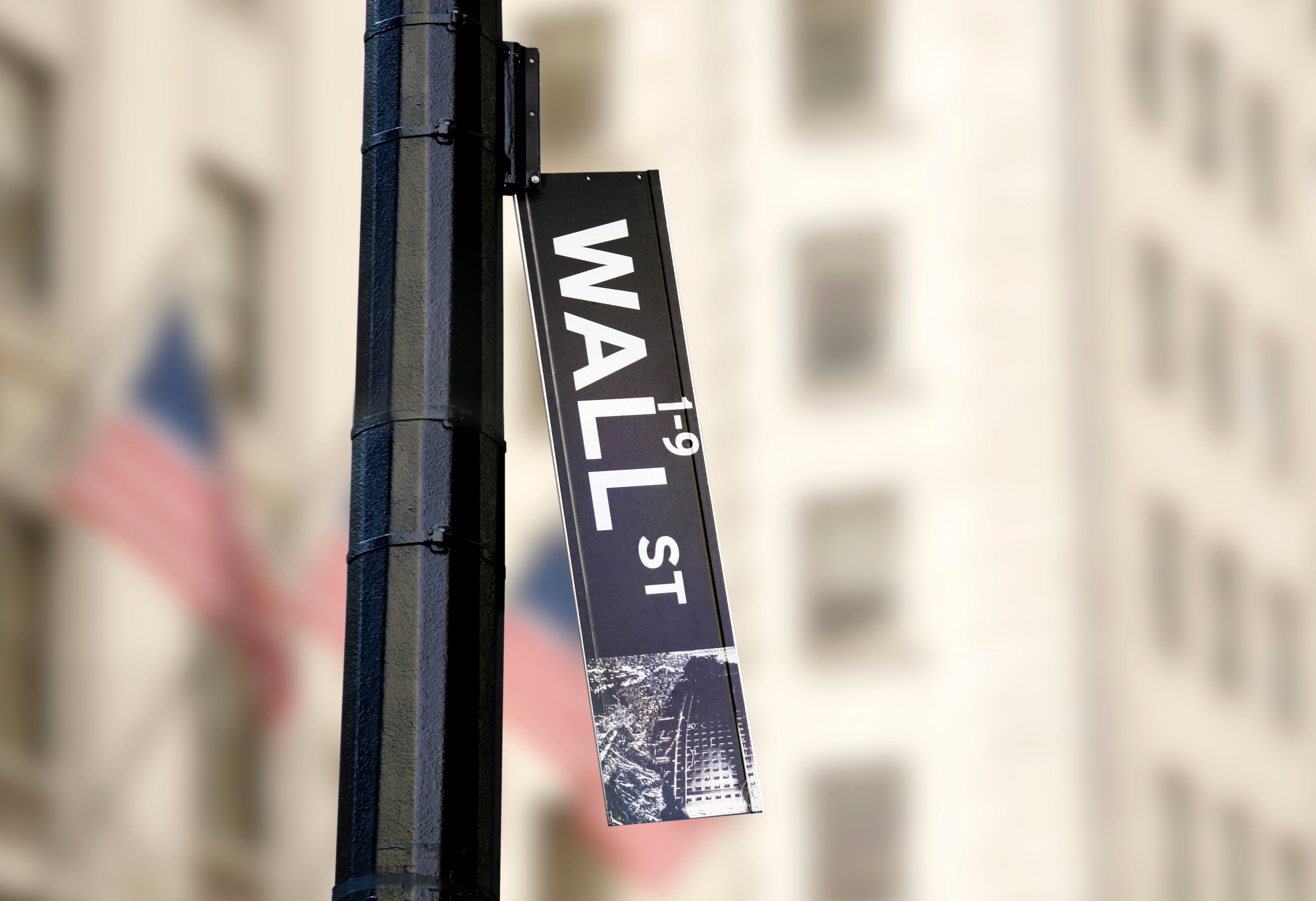 A Wall Street sign falling off its signpost.