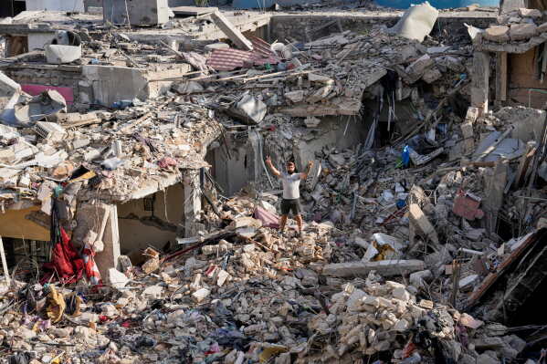 A man who returns to his village following the announcement of an initial ceasefire agreement between the United States and Iran, flashes victory sign as he stands on the rubble of his destroyed house in Nabatiyeh town, southern Lebanon, Tuesday, June 16, 2026. (AP Photo/Hussein Malla)