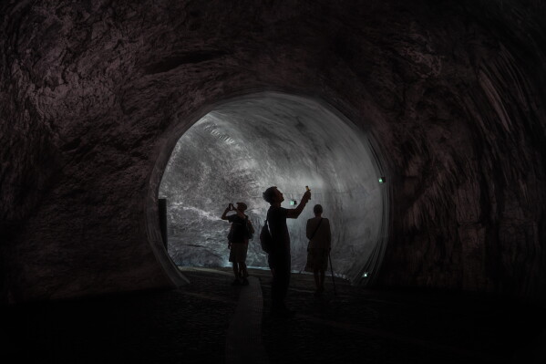 Visitors walk into the artwork "The Pont Neuf Cave" by French street artist JR on the Pont Neuf bridge, Tuesday, June 16, 2026, in Paris, open to the public from June 15 to 28. (AP Photo/Aurelien Morissard)