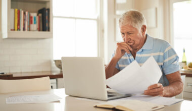 Shot of a senior man looking stressed while doing the household finances on a laptop in his kitchen.