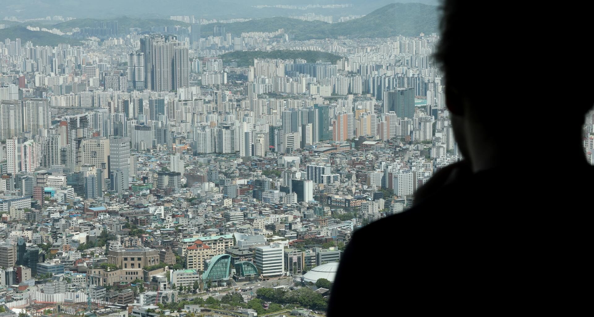 A visitor looks out over apartment complexes from Mount Nam in Seoul, May 8. Yonhap